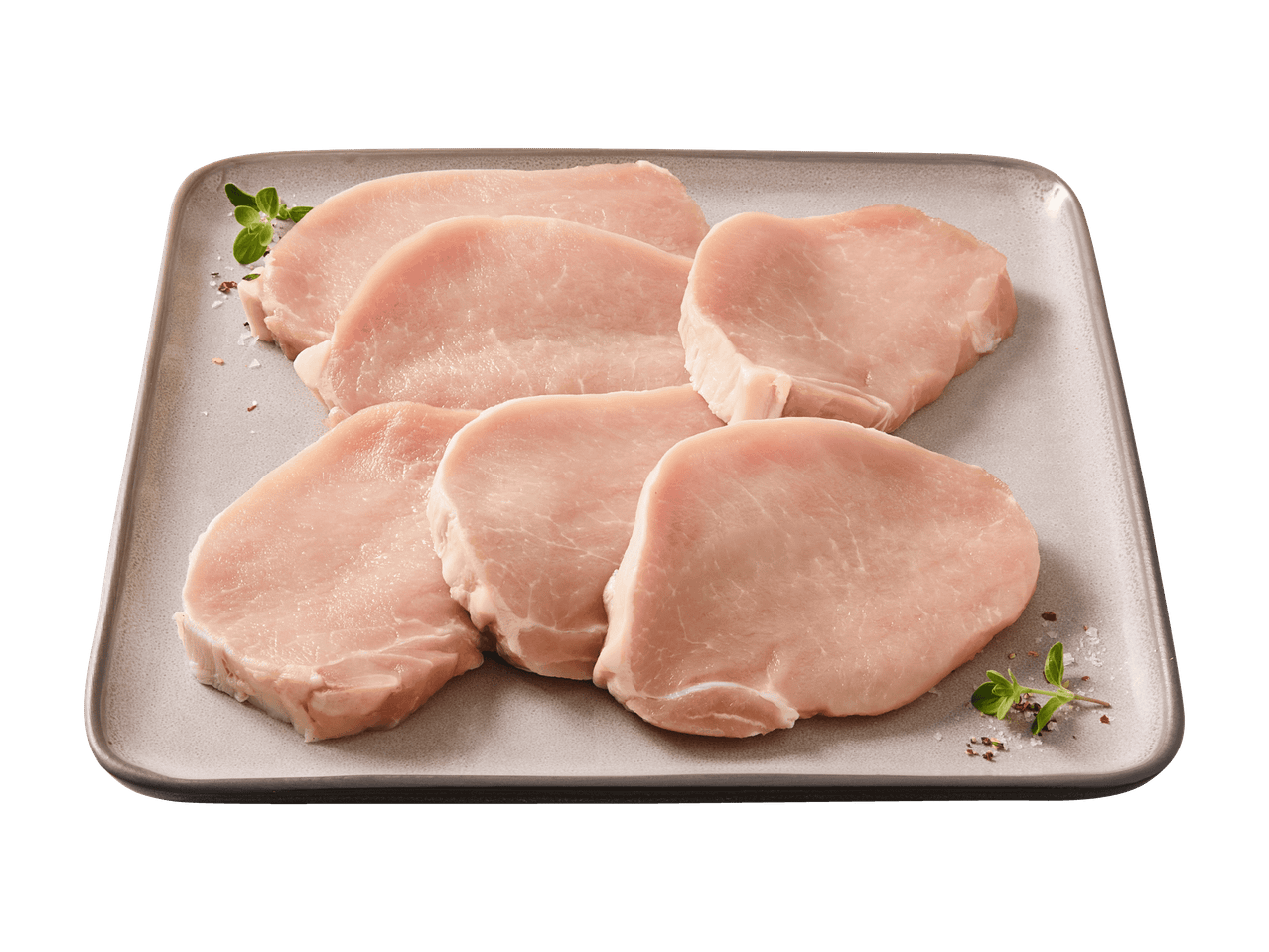 Rohe Schweinekoteletts auf einer grauen Platte, garniert mit Kräutern und Gewürzen.