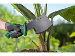 Mână înmănușată ținând o secure PARKSIDE® lângă o plantă tânără.