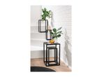 Black metal nesting tables with plants and decor against a white brick wall.