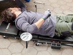 A man uses a Parkside Performance creeper to work under a car.