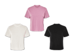 Drei einfache T-Shirts in Weiß, Rosa und Schwarz.