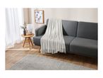 Living room with a gray sofa, white throw blanket, and light wood flooring.