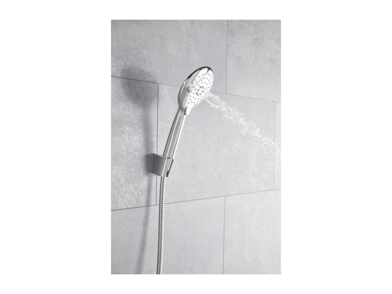 Chrome shower head spraying water, mounted on a grey tiled wall.