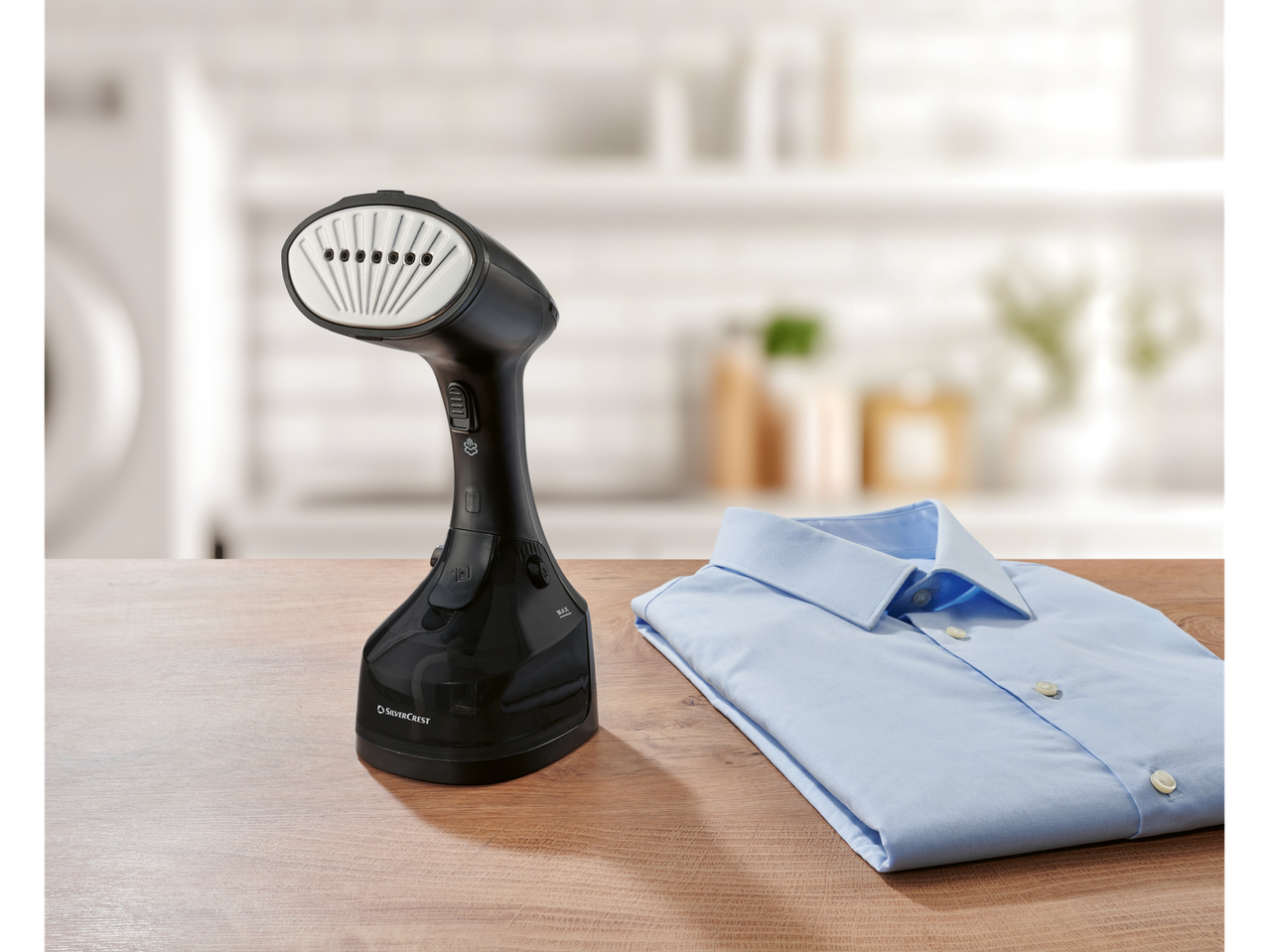 SILVERCREST® Garment Steamer and a folded blue shirt on a wooden table.