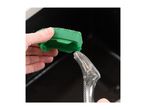 Hand holding a green dishwashing sponge with a clear soap dispenser in a sink.