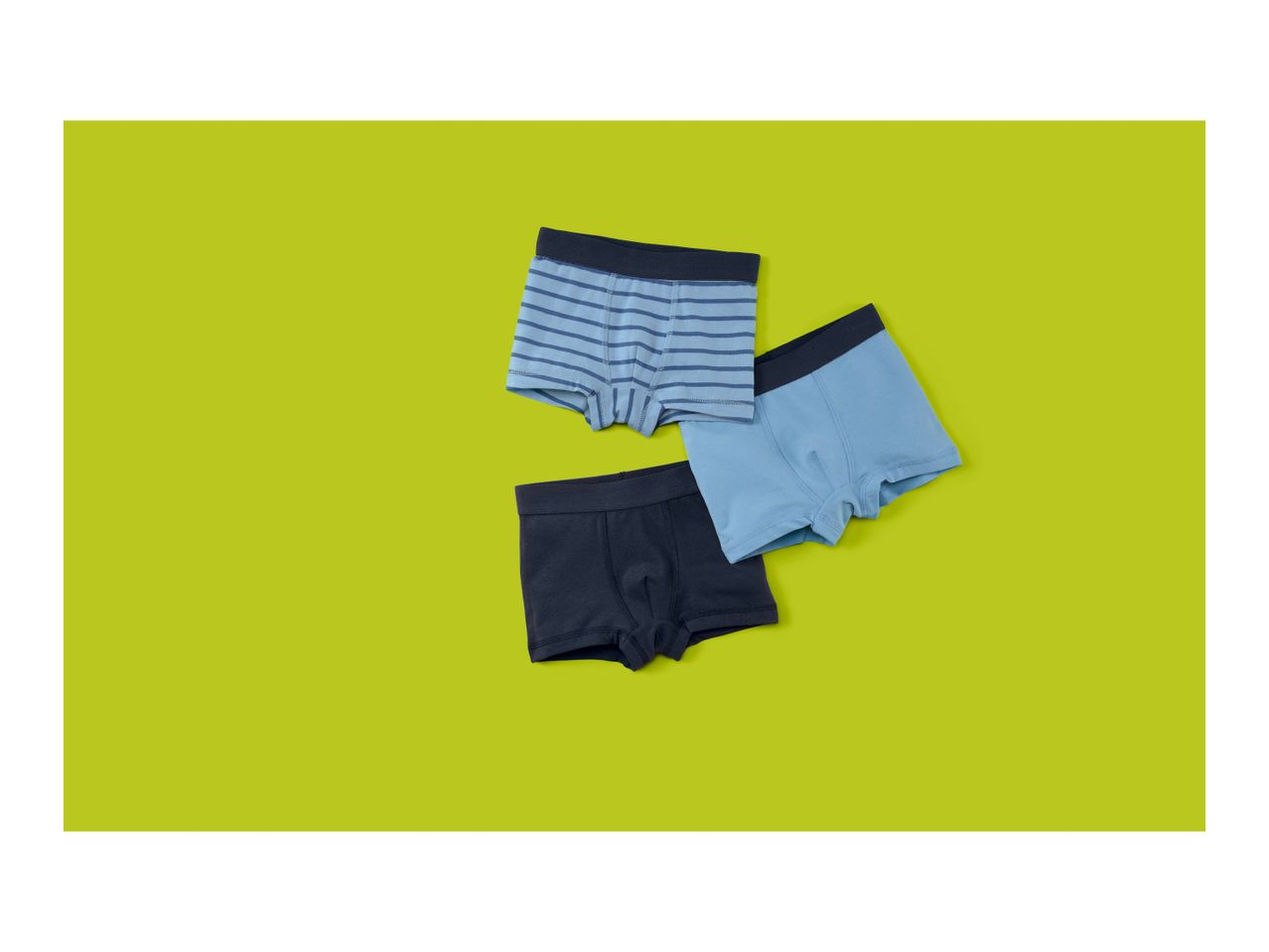 Three pairs of boys' boxer briefs in blue, striped blue, and dark blue on a lime green background.