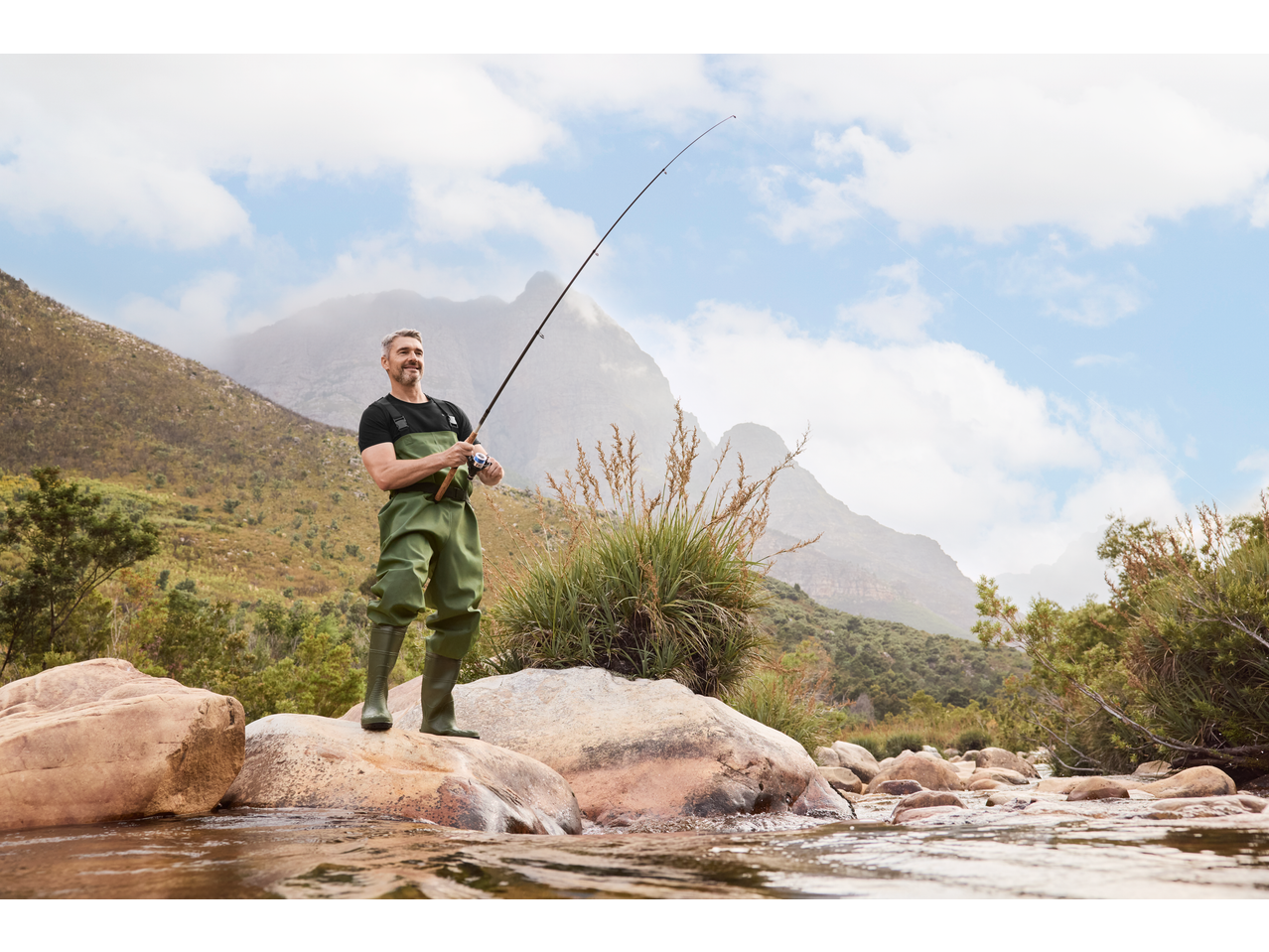 Mann in CRIVIT Wathose beim Angeln in einem Gebirgsfluss.