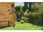 Man mowing lawn and woman trimming hedges in a sunny garden.