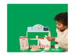 Child playing with a wooden toy bakery stand, featuring a menu and various pastries.