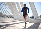 Man running in CRIVIT sports shorts and vest under a modern archway.