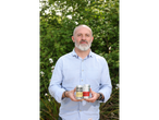 A man holds two cans of Steeper Culture kombucha, including 'The Haymaker' Ginger & Lemon.