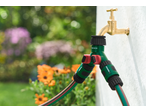 Conjunto de ligação de rega PARKSIDE com mangueira verde e torneira de latão no jardim.