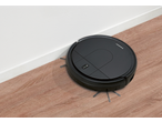 Aspirador robótico SILVERCREST® preto em piso de madeira, a limpar junto à parede