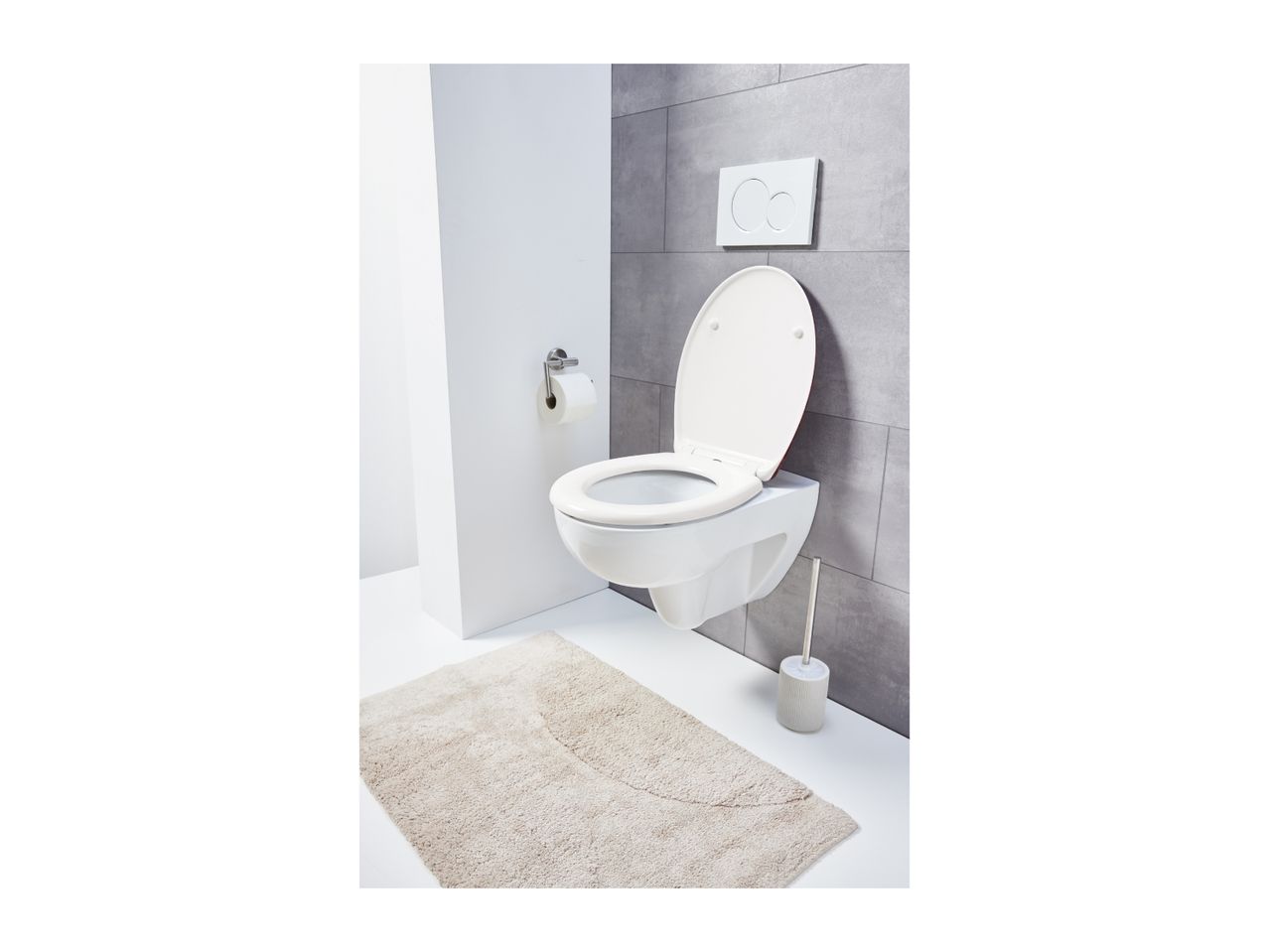 A modern bathroom with a wall-mounted toilet, toilet paper holder, and a bath mat.