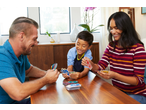 Family playing UNO card game at a wooden table, smiling and laughing.