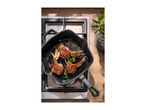 Lamb chops and vegetables grilling in a cast iron pan on a gas hob.
