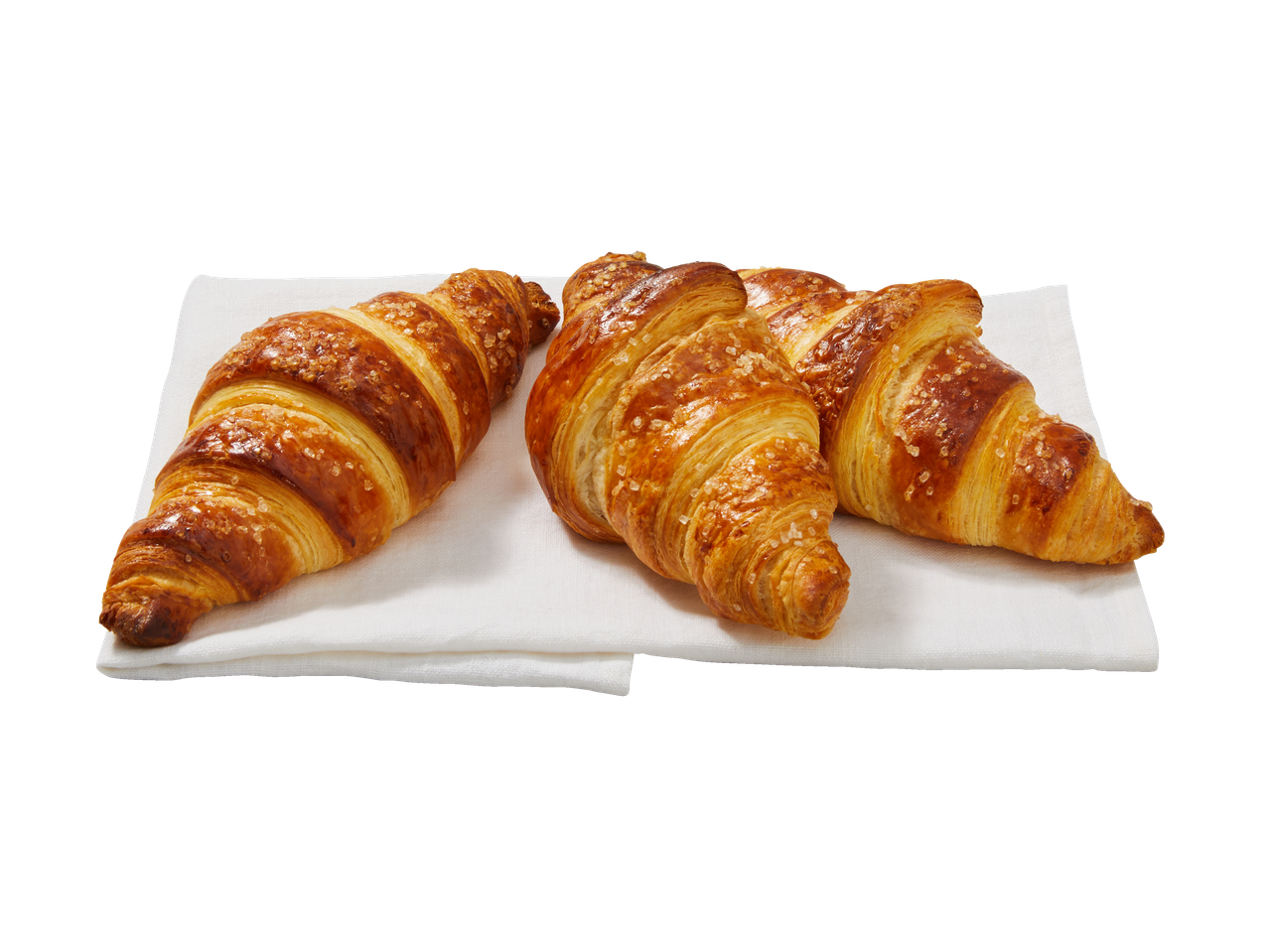Trys auksiniai XXL kruasanai, pabarstyti cukrumi, ant baltos servetėlės.