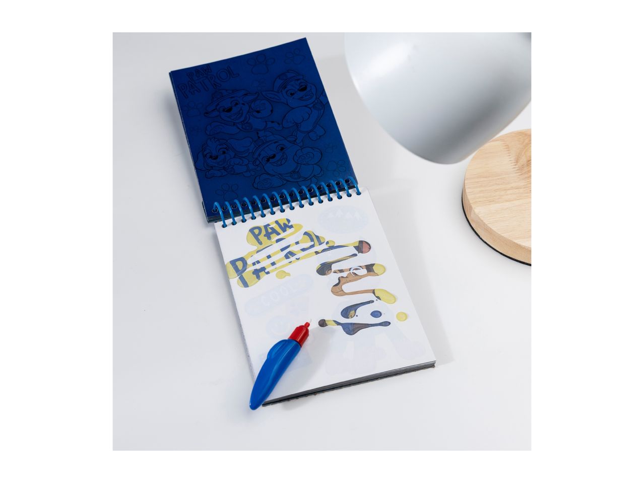 A Paw Patrol spiral notebook with a water pen, showing colorful designs on a white surface.