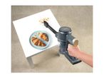 A handheld vacuum cleaner being used to clean up crumbs on a white table.