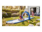 Two children playing on a shark-themed water slide in a sunny garden.