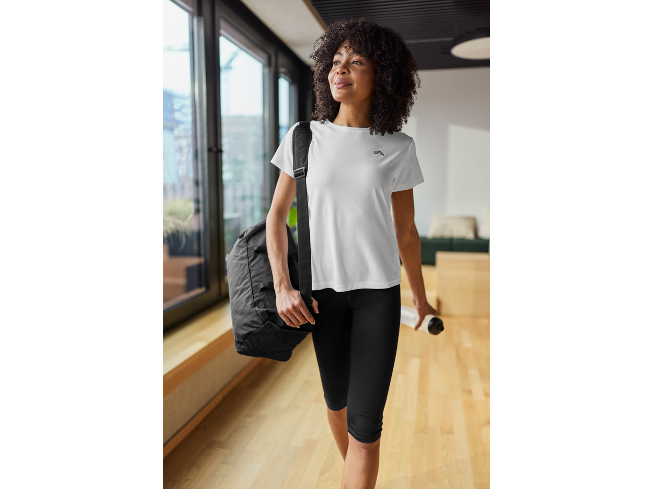 Woman in CRIVIT sportswear carrying a black sports bag and water bottle.