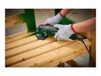 Hands in protective gloves using a multi-tool to sand a wooden bench.