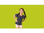 Smiling girl in a navy blue Lupilu Kids' T-Shirt with strawberry print and pink shorts.