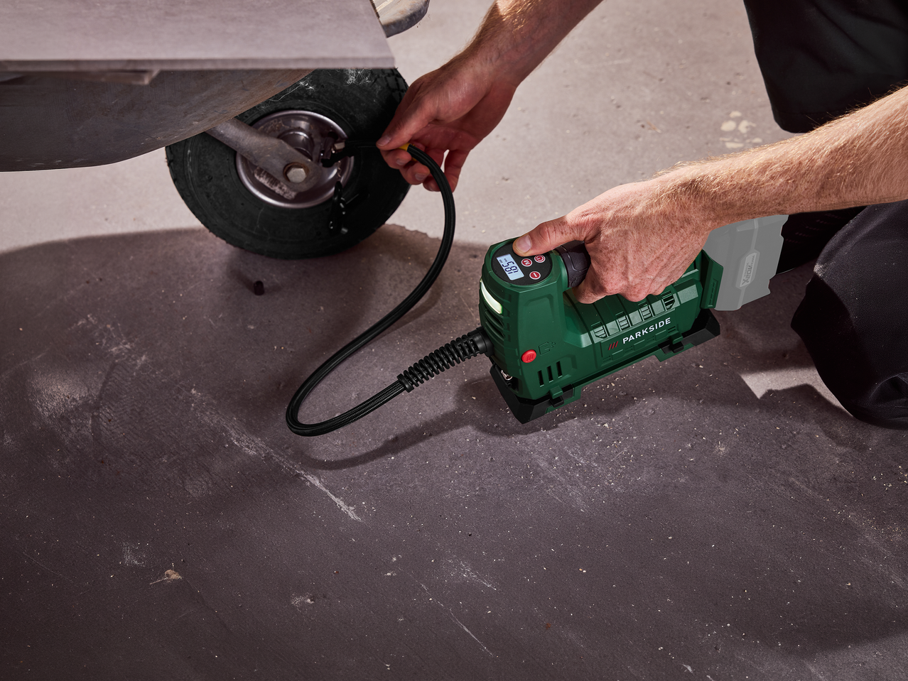 Άνδρας φουσκώνει ελαστικό με φορητό συμπιεστή αέρα.