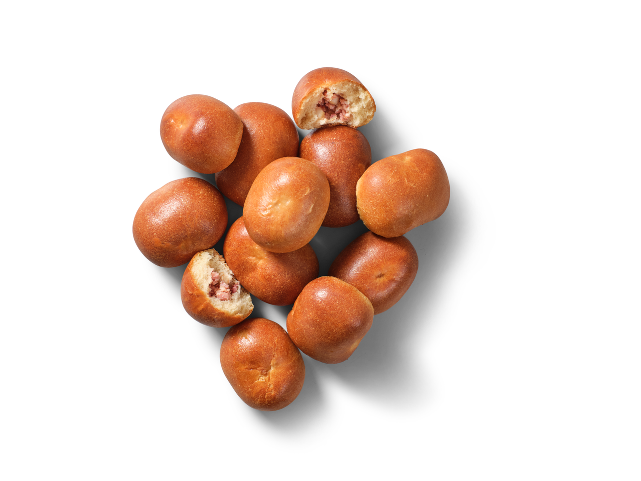 Minu Leib Cannelé ar pistāciju pildījumu, zeltaini brūnu konditorejas izstrādājumu kaudze, viens atvērts, lai parādītu pildījumu.