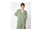 Woman in a sage green textured V-neck top and matching skirt