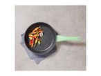 Overhead view of a black speckled frying pan with a green handle, filled with roasted vegetables, on a gray surface.