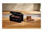 Black retro bread bin with the year 1973 on a wooden countertop next to sliced bread
