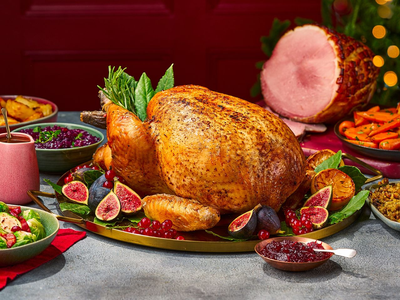 A festive Christmas dinner spread with a roasted turkey, glazed ham, and various side dishes.