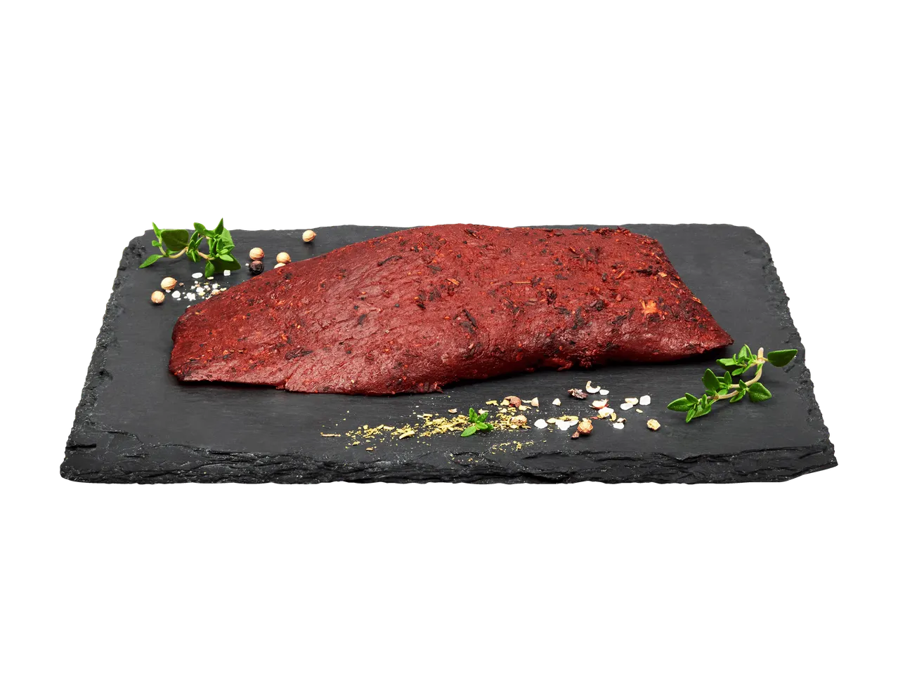 Morceau de viande marinée sur une planche d'ardoise avec herbes et épices.