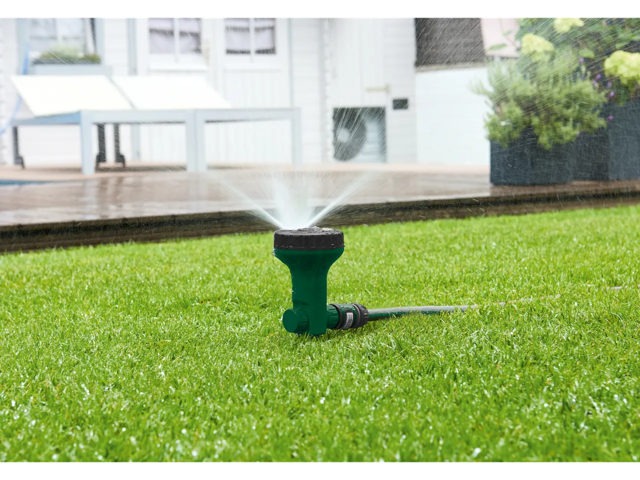 Un irrigatore verde annaffia un prato.
