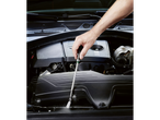 A hand uses a Parkside® magnetic pickup tool to retrieve an object from a car engine.