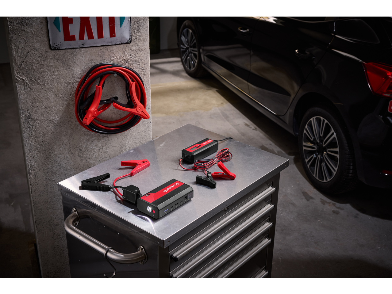 ULTIMATE SPEED® Portable Jump Starter with Power Bank and battery charger on a metal workbench in a garage.