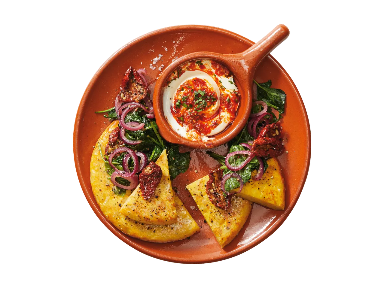 Spaanse tortilla in stukjes gesneden, geserveerd met yoghurtsaus, spinazie en gedroogde tomaten.