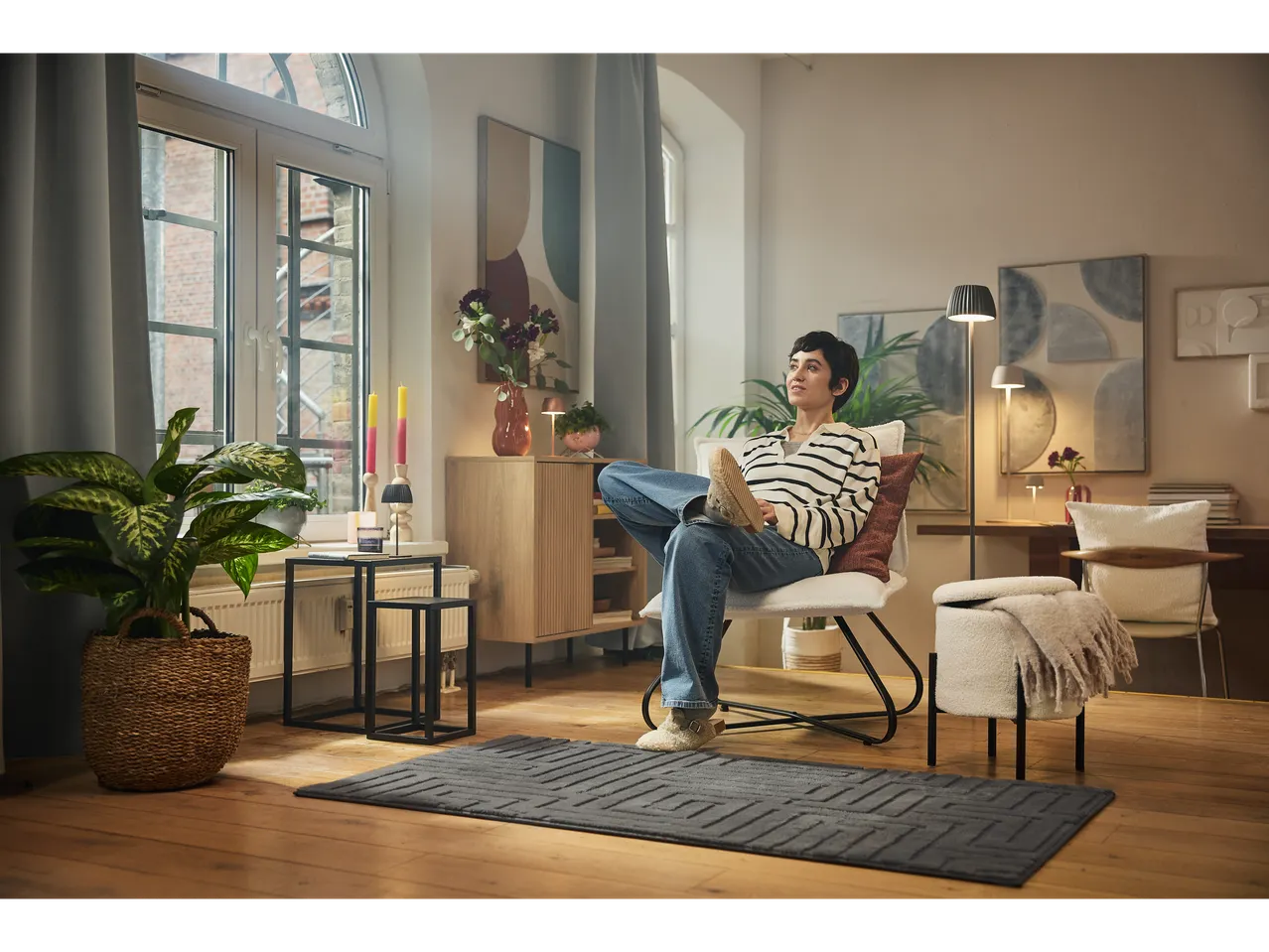 Femeie așezată pe scaun cu taburet de depozitare și covor în sufragerie.