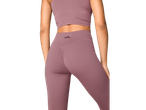 Mulher em leggings e top desportivo CRIVIT® roxos, vista traseira.