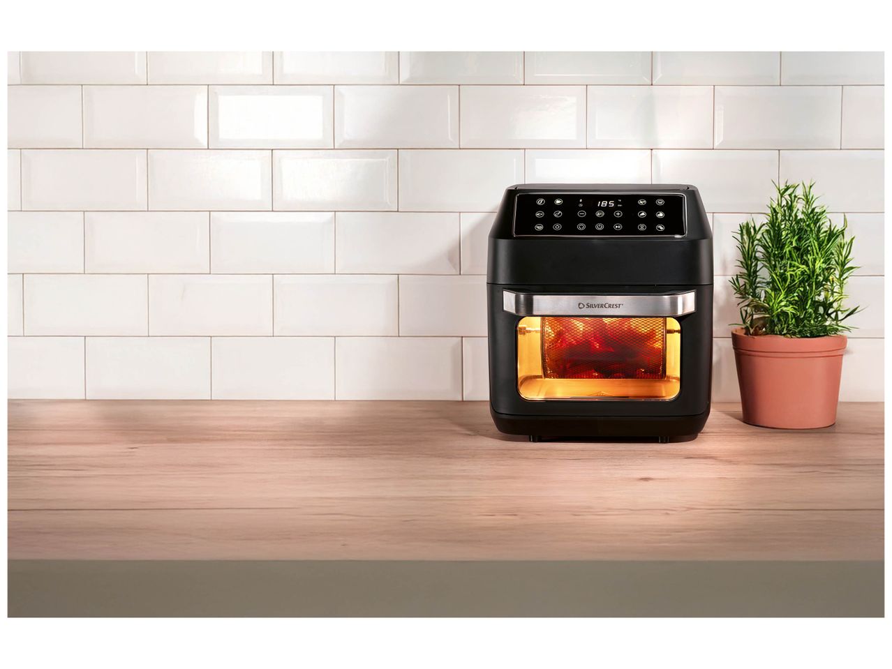 Friteuse à air chaud Silvercrest noire sur un plan de travail en bois avec un mur carrelé blanc.