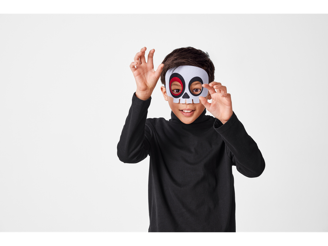 A child wearing a white skull mask and black long-sleeve shirt.