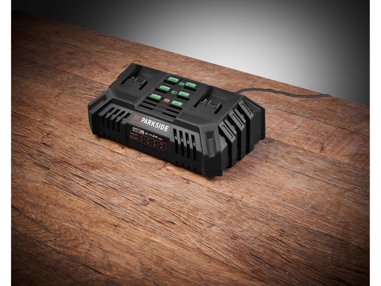 Зарядно устройство за батерии Parkside® X 20 V Team 2x4,5 A макс. върху дървена маса.