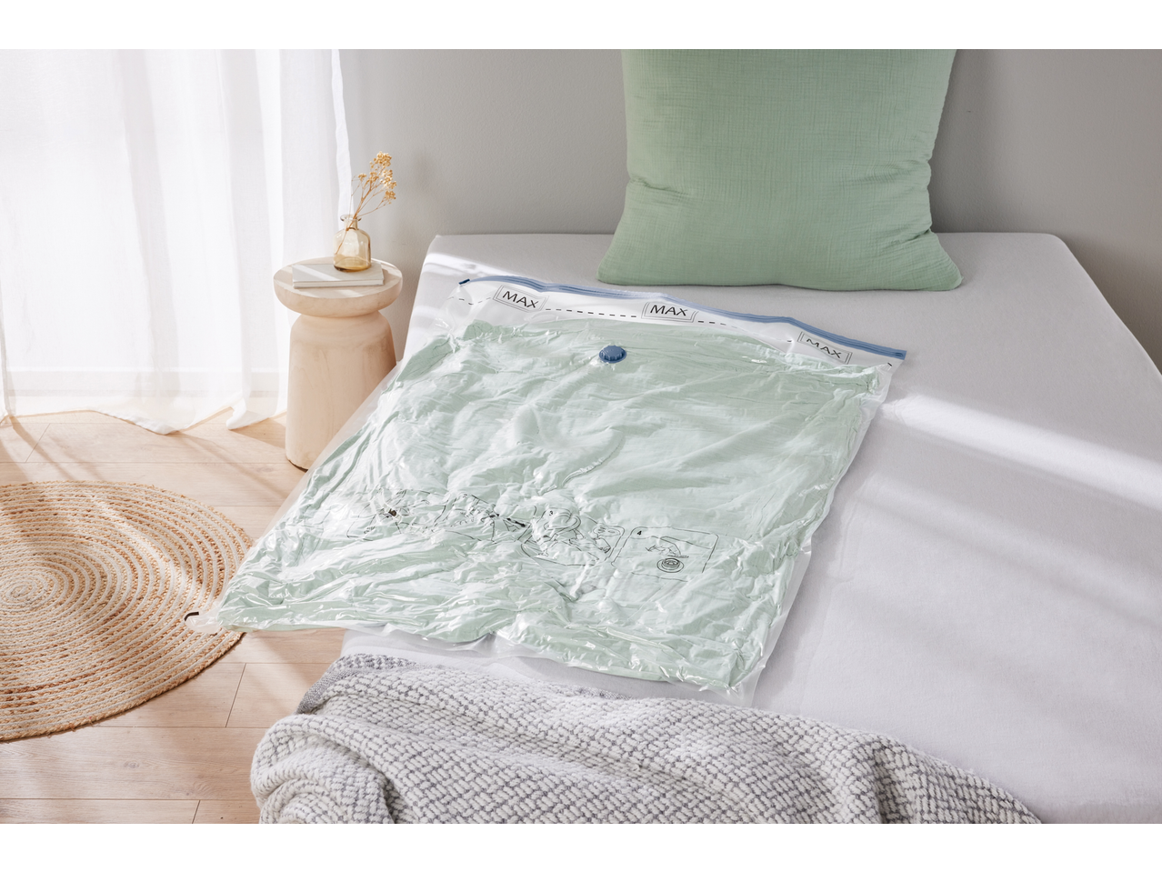 Vacuum storage bag with a light green duvet inside, on a bed with a matching pillow.