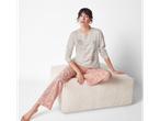 Woman in esmara® pajamas with floral print, sitting on an ottoman.