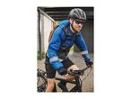 Man in a blue cycling jacket, helmet, and sunglasses riding a bicycle.