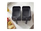 Two silicone air fryer liners placed inside dual air fryer baskets on a kitchen counter.