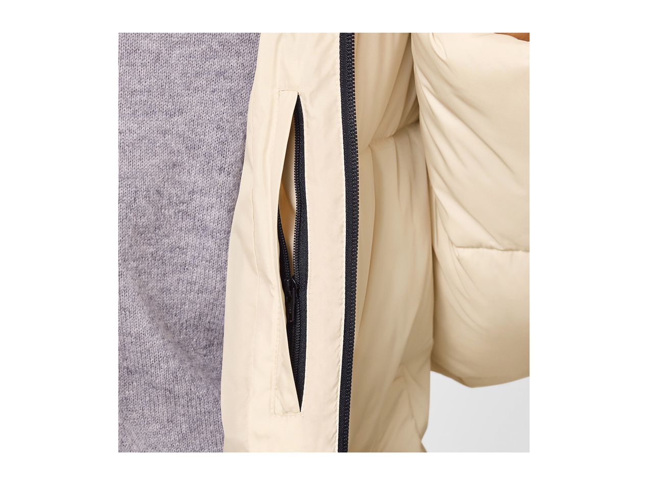Close-up of a beige puffer jacket with a black zipper and a grey sweater underneath