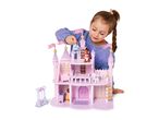 A young girl playing with a pink wooden dollhouse and small doll figures.