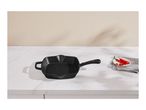 Black cast iron grill pan on a white marble countertop with red chili peppers.